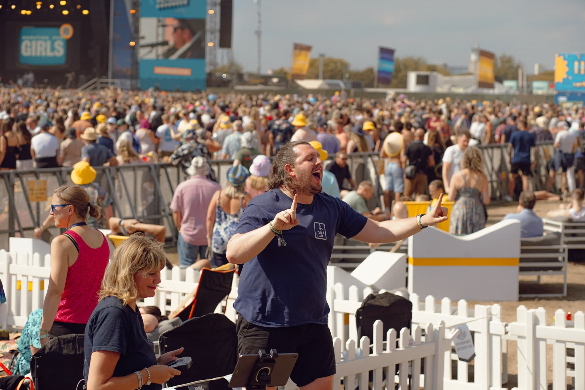 BSL interpreter signing at a festival with stage behind