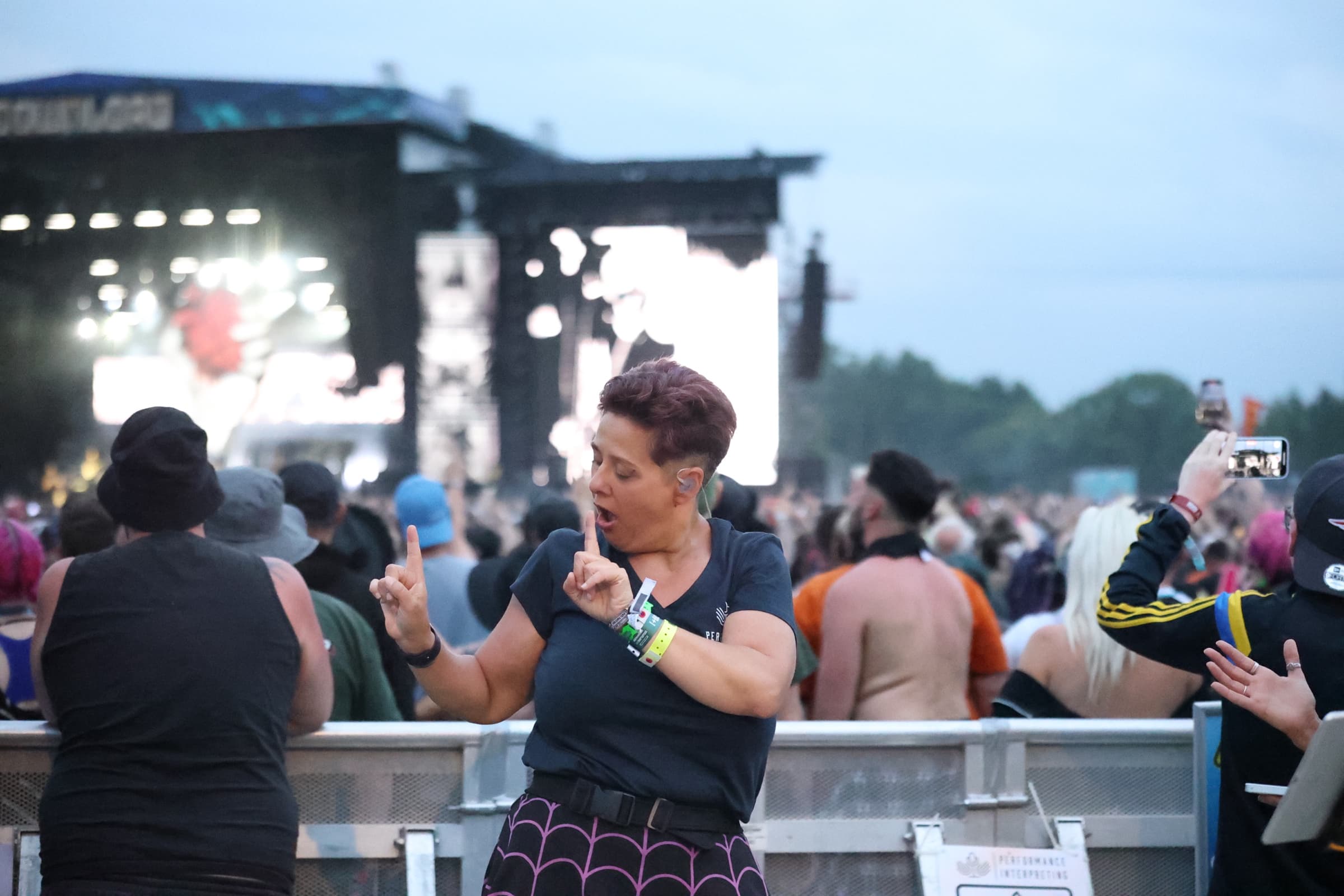 PI interpreter signing in front of festival main stage crowd at dusk