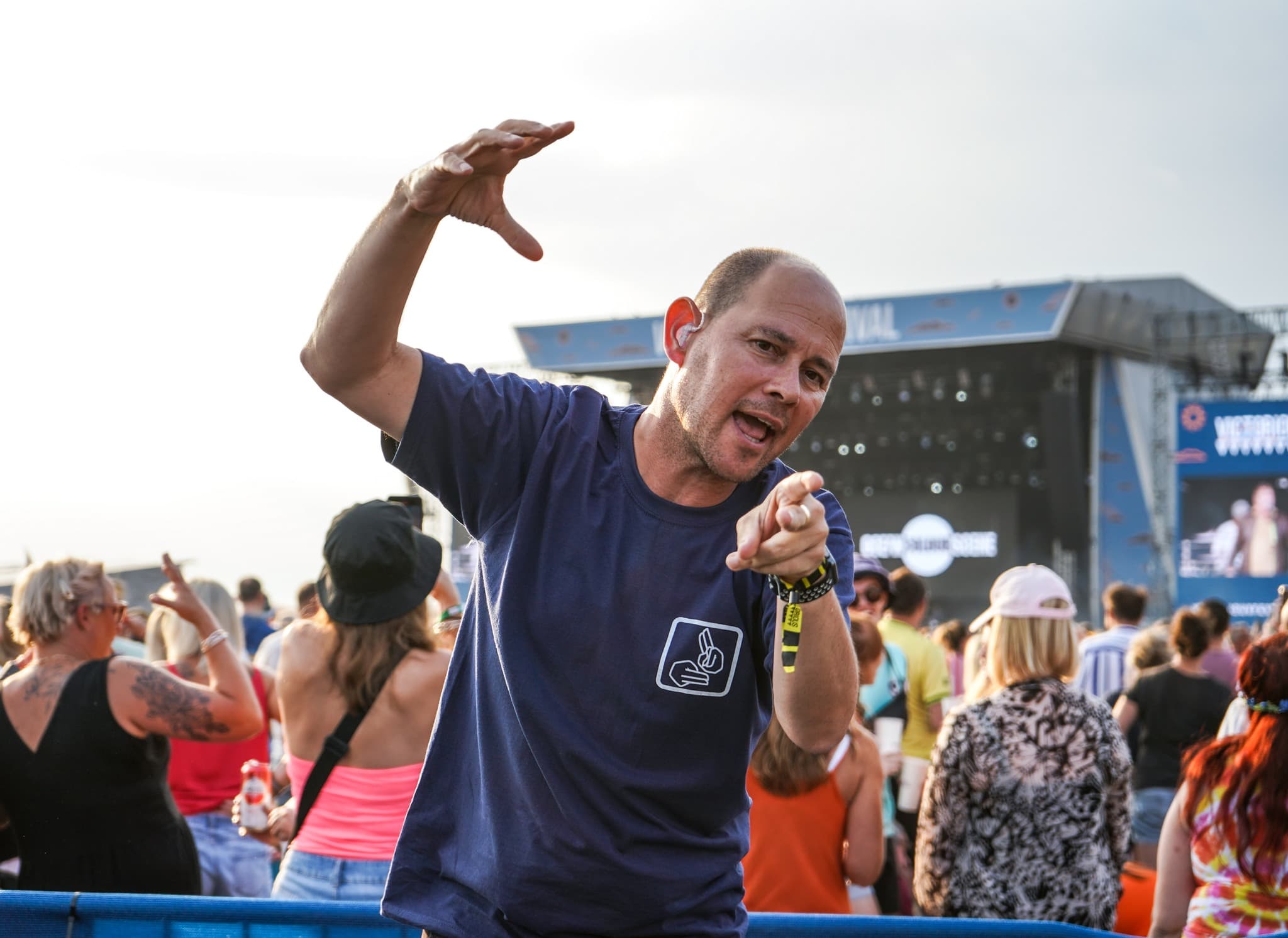 BSL interpreter signing at a festival with stage behind